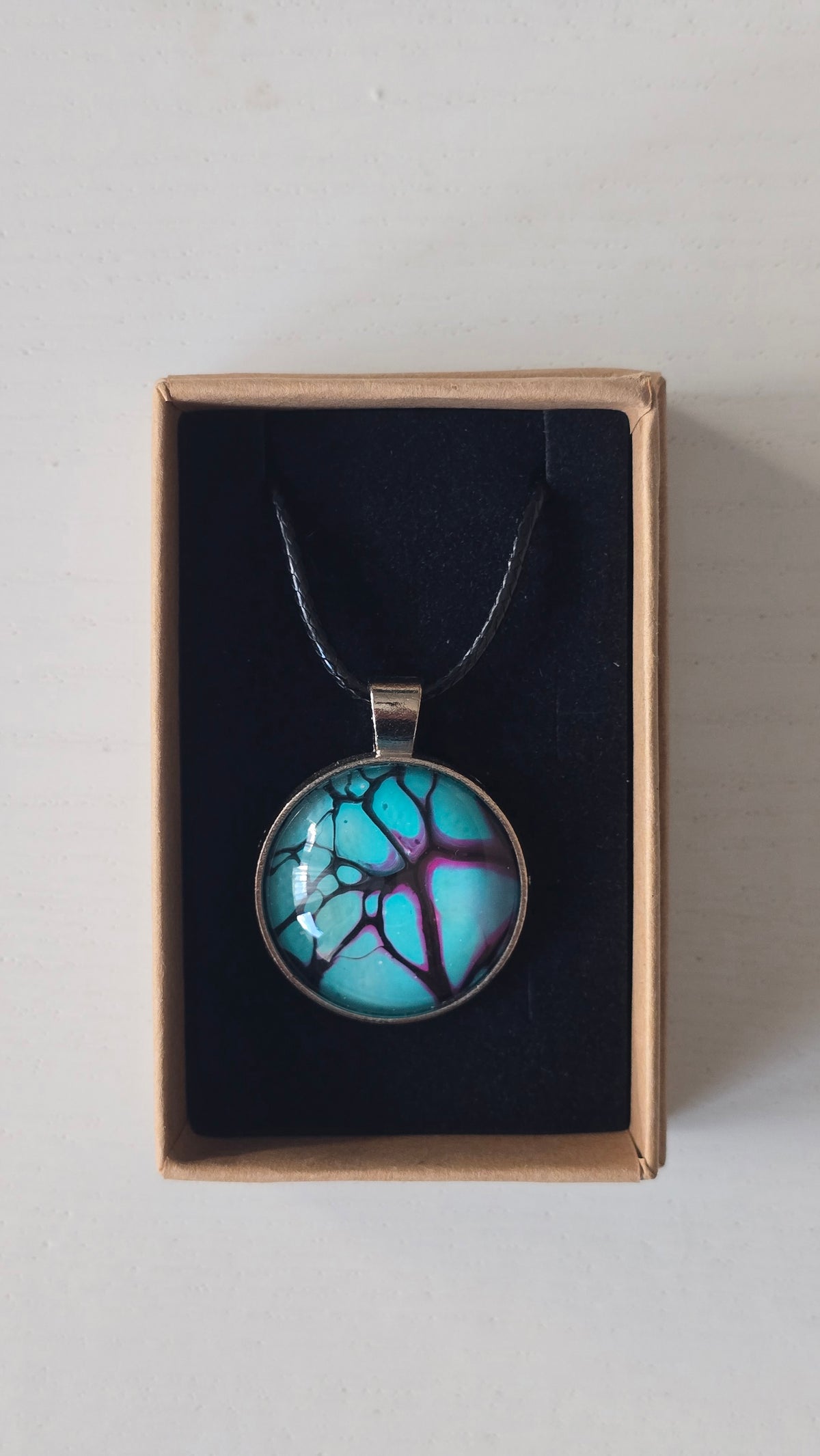 Runde Cabochon-Kette in leuchtendem Türkis mit verzweigten Strukturen in Violett, Pink und Schwarz.