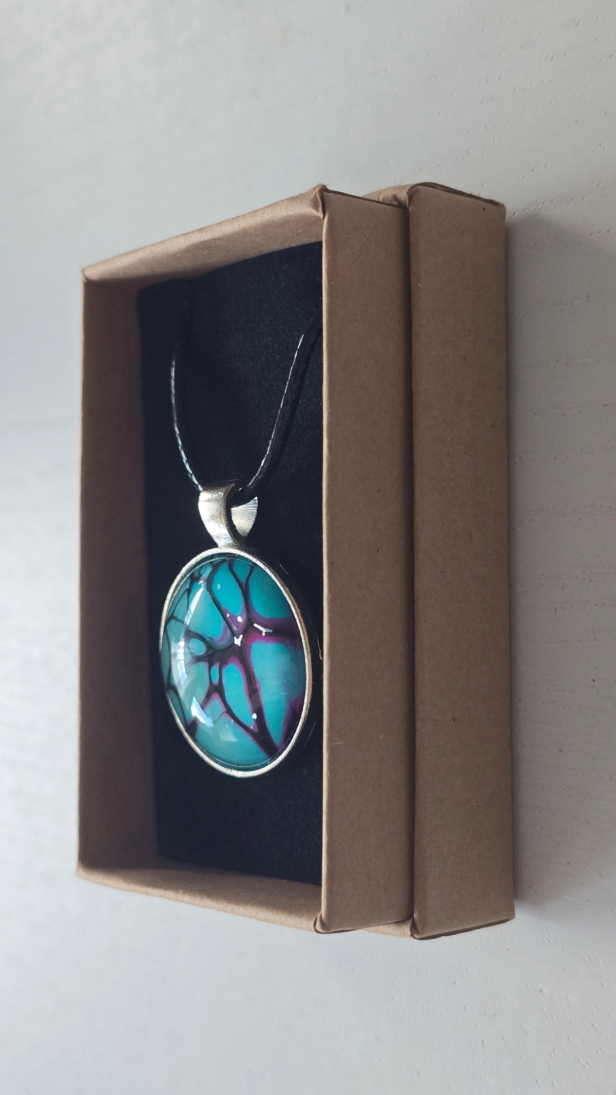 Runde Cabochon-Kette in leuchtendem Türkis mit verzweigten Strukturen in Violett, Pink und Schwarz.