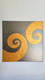Quadratisches Leinwandbild mit warmgrauem Hintergrund und zwei grossen, plastisch strukturierten goldenen Spiralen.