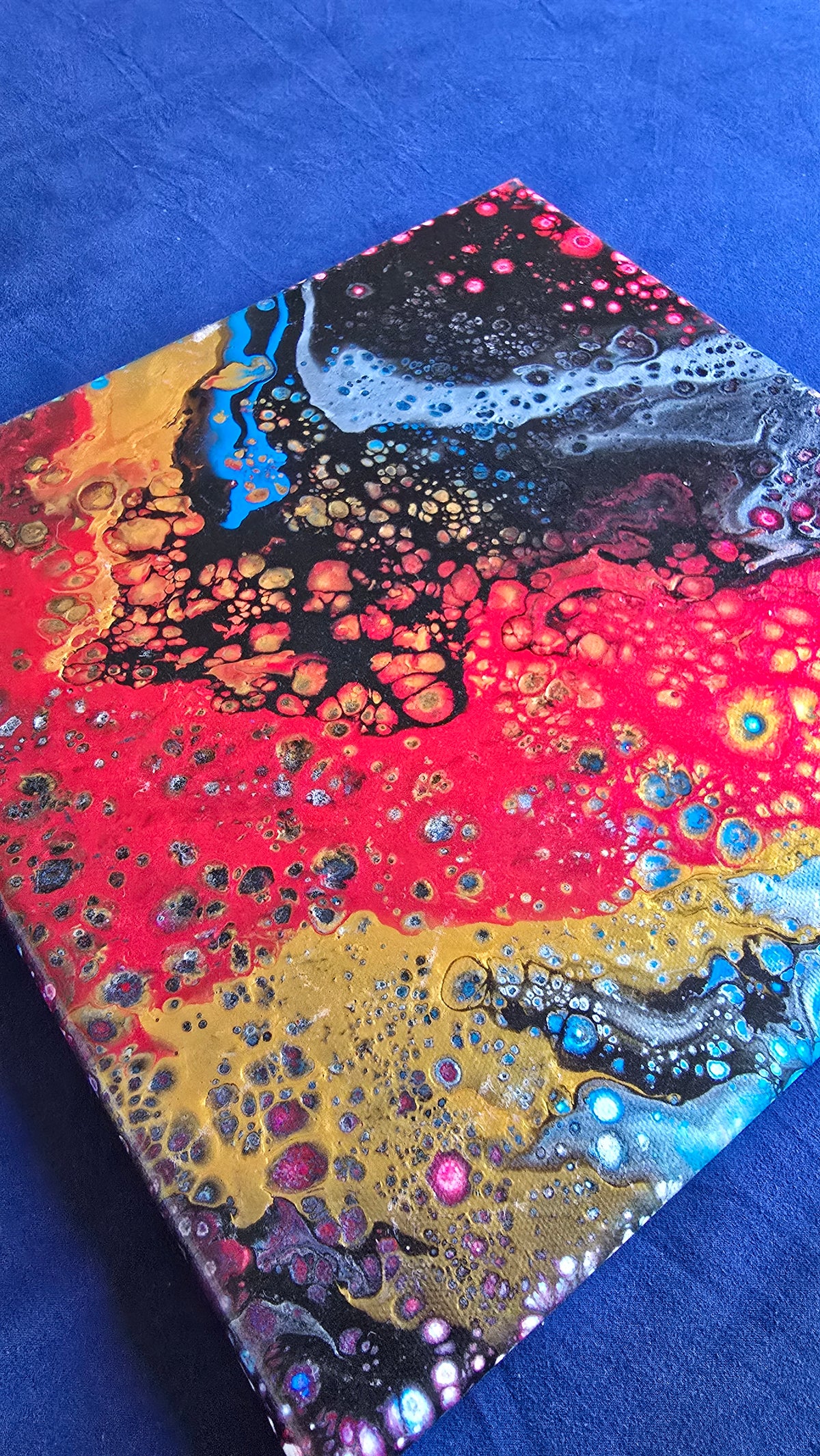 Drei abstrakte Leinwandbilder in unterschiedlichen Grössen mit fliessenden Farbflächen und feinen Zellstrukturen in Rot, Blau, Gold, Schwarz und Weiss.