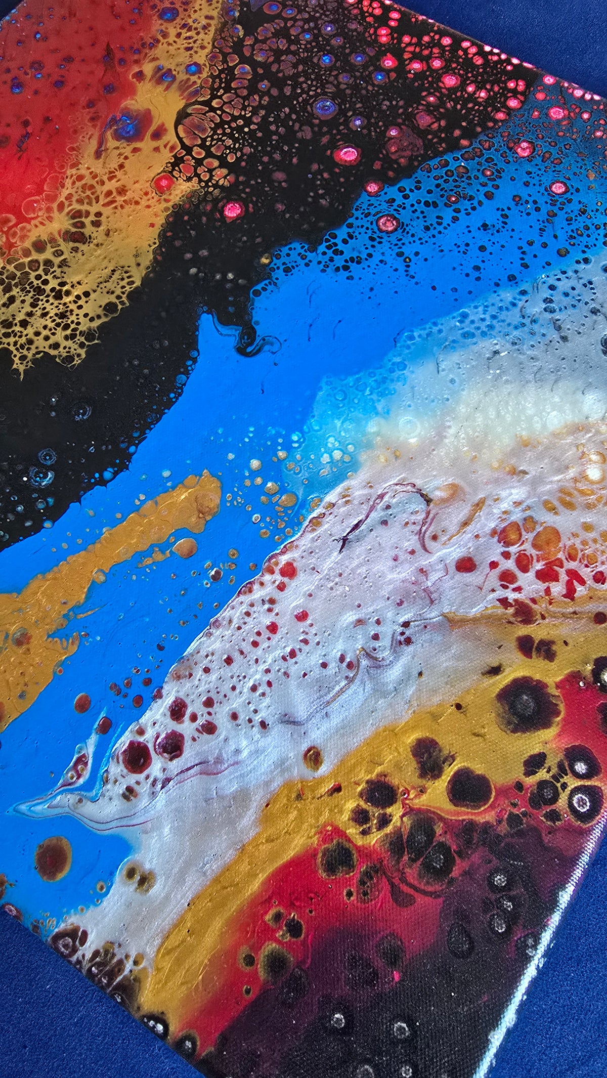 Drei abstrakte Leinwandbilder in unterschiedlichen Grössen mit fliessenden Farbflächen und feinen Zellstrukturen in Rot, Blau, Gold, Schwarz und Weiss.