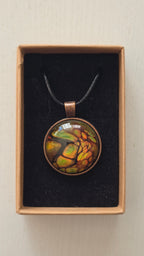 Runde Cabochon Kette Solas Forest Flame in Grün, Orange und Gold mit dunklen Strukturen, bronzefarbener Fassung und schwarzem Band.