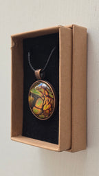 Runde Cabochon Kette Solas Forest Flame in Grün, Orange und Gold mit dunklen Strukturen, bronzefarbener Fassung und schwarzem Band.
