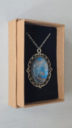 Ovale Cabochon Kette Solas Frozen Current in leuchtendem Blau, Silber und Grau mit verzierter silberfarbener Fassung und Metallkette.