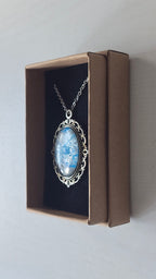 Ovale Cabochon Kette Solas Frozen Current in leuchtendem Blau, Silber und Grau mit verzierter silberfarbener Fassung und Metallkette.