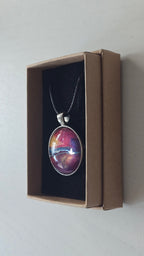 Runder Cabochon-Anhänger an schwarzem Band mit geschichtetem Muster in Fuchsia, Pink, Violett, Blau, Türkis und einem goldenen Akzent.