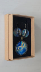 Rundes Cabochon-Schmuckset mit Anhänger und Ohrringen an schwarzem Band, mit organischem Muster in Blau, Türkis und Aquatönen sowie goldenen Akzenten.