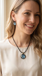 Frau trägt rundes Cabochon-Schmuckset mit Anhänger und Ohrringen an schwarzem Band, mit marmoriertem Muster in Blau, Cyan, Silber-/Perlgrau, Anthrazit und Schwarz.