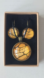 Rundes Cabochon-Schmuckset mit Halskettenanhänger und passenden Ohrringen in warmen Gold- und Bernsteintönen mit feinen dunklen Linien.