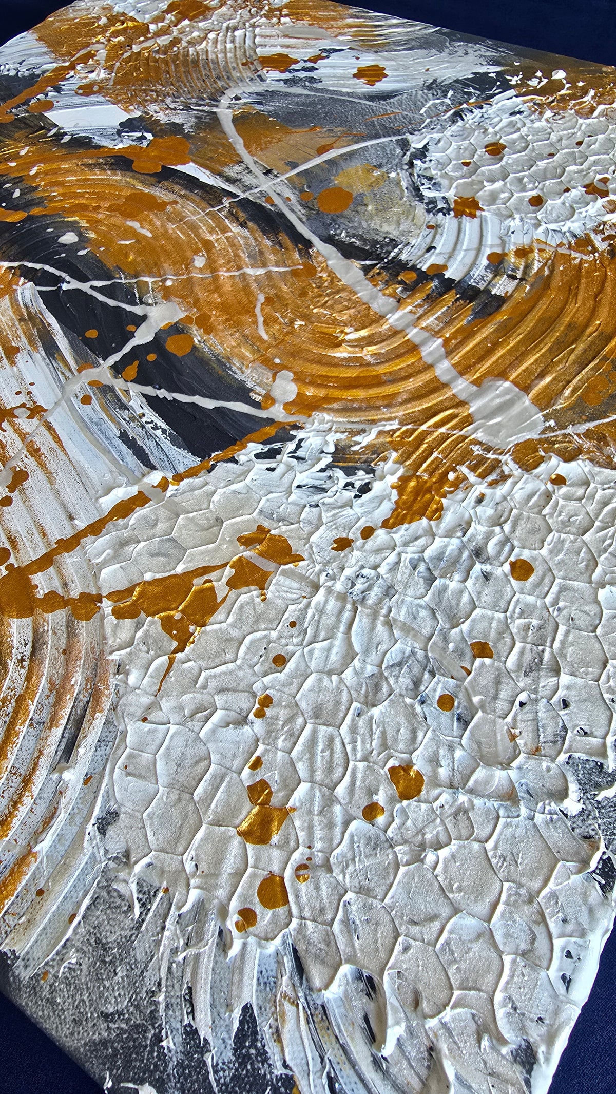 Zwei versetzt angeordnete abstrakte Strukturbilder in Gold, Weiss und Grau mit erhabenen Flächen, geschwungenen Linien und kreisförmigen Mustern.