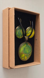 Rundes Cabochon Schmuckset mit grossem Kettenanhänger und zwei passenden Ohrringen in Grün, Gelb und Gold mit organisch fliessenden Mustern, bronzefarbenen Fassungen und schwarzem Band.