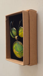 Rundes Cabochon Schmuckset mit grossem Kettenanhänger und zwei passenden Ohrringen in Grün, Gelb und Gold mit organisch fliessenden Mustern, bronzefarbenen Fassungen und schwarzem Band.