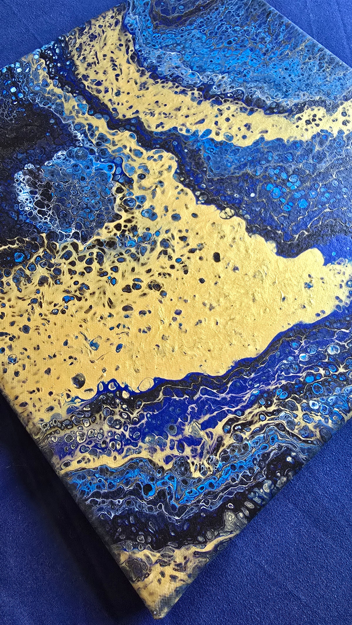 Quadratisches abstraktes Leinwandbild in kräftigem Blau, Dunkelblau und Schwarz mit grossen goldenen Flächen und feinen Zellstrukturen.