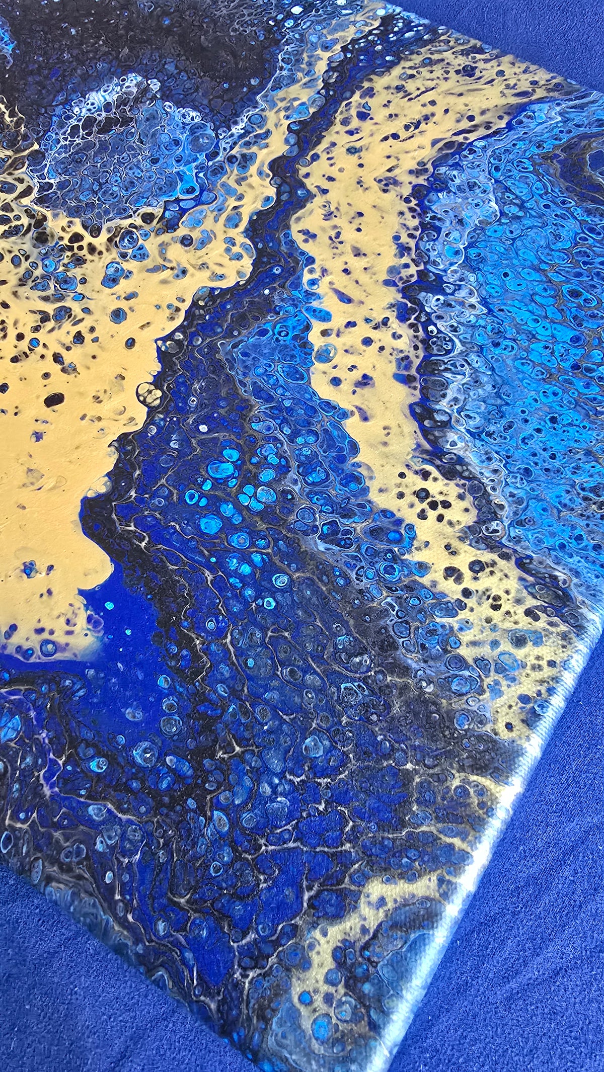 Quadratisches abstraktes Leinwandbild in kräftigem Blau, Dunkelblau und Schwarz mit grossen goldenen Flächen und feinen Zellstrukturen.