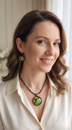 Frau trägt rundes Cabochon-Schmuckset mit grossem Halskettenanhänger und zwei passenden Ohrringen in Grün und Limette mit dunklen organischen Konturen.