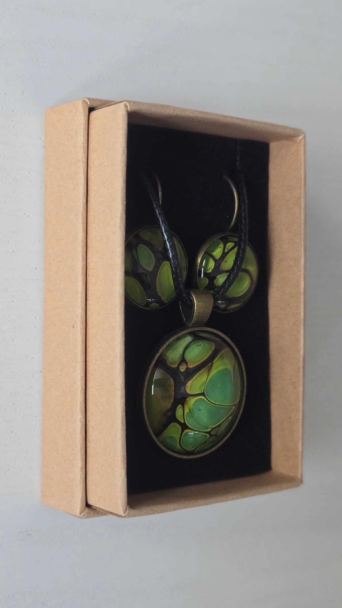 Rundes Cabochon-Schmuckset mit grossem Halskettenanhänger und zwei passenden Ohrringen in Grün und Limette mit dunklen organischen Konturen.