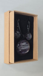 Rundes Cabochon-Schmuckset mit Anhänger und Ohrringen an schwarzem Band, mit geschichtetem Muster in Schwarz, Anthrazit, Violett und silbrigem Schimmer.