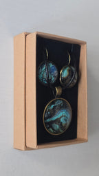 Cabochon-Schmuckset mit rundem Anhänger und zwei Ohrringen mit marmoriertem Muster in Türkis, Petrol, Blau und Schwarz mit goldig-bronzefarbenen Akzenten.