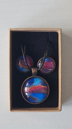 Rundes Cabochon-Schmuckset mit Anhänger und Ohrringen an schwarzem Band, mit abstraktem Muster in Blau, Cyan, Pink und Violett sowie feinen goldenen Linien.