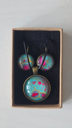 Rundes Cabochon-Schmuckset mit Halskettenanhänger und passenden Ohrringen in Türkis und kräftigem Pink mit feinen goldenen Linien.