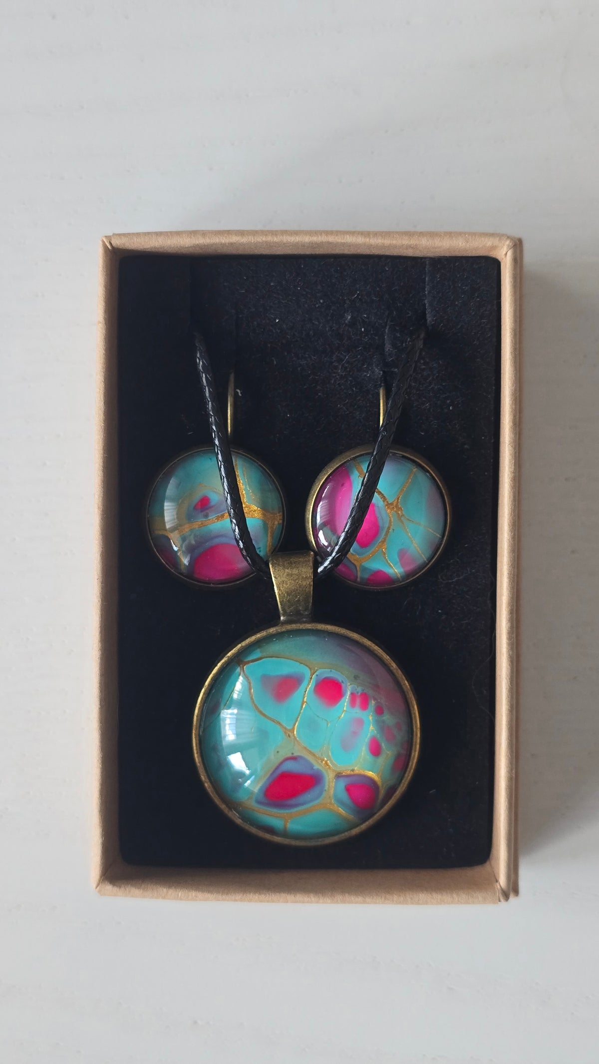 Rundes Cabochon-Schmuckset mit Halskettenanhänger und passenden Ohrringen in Türkis und kräftigem Pink mit feinen goldenen Linien.