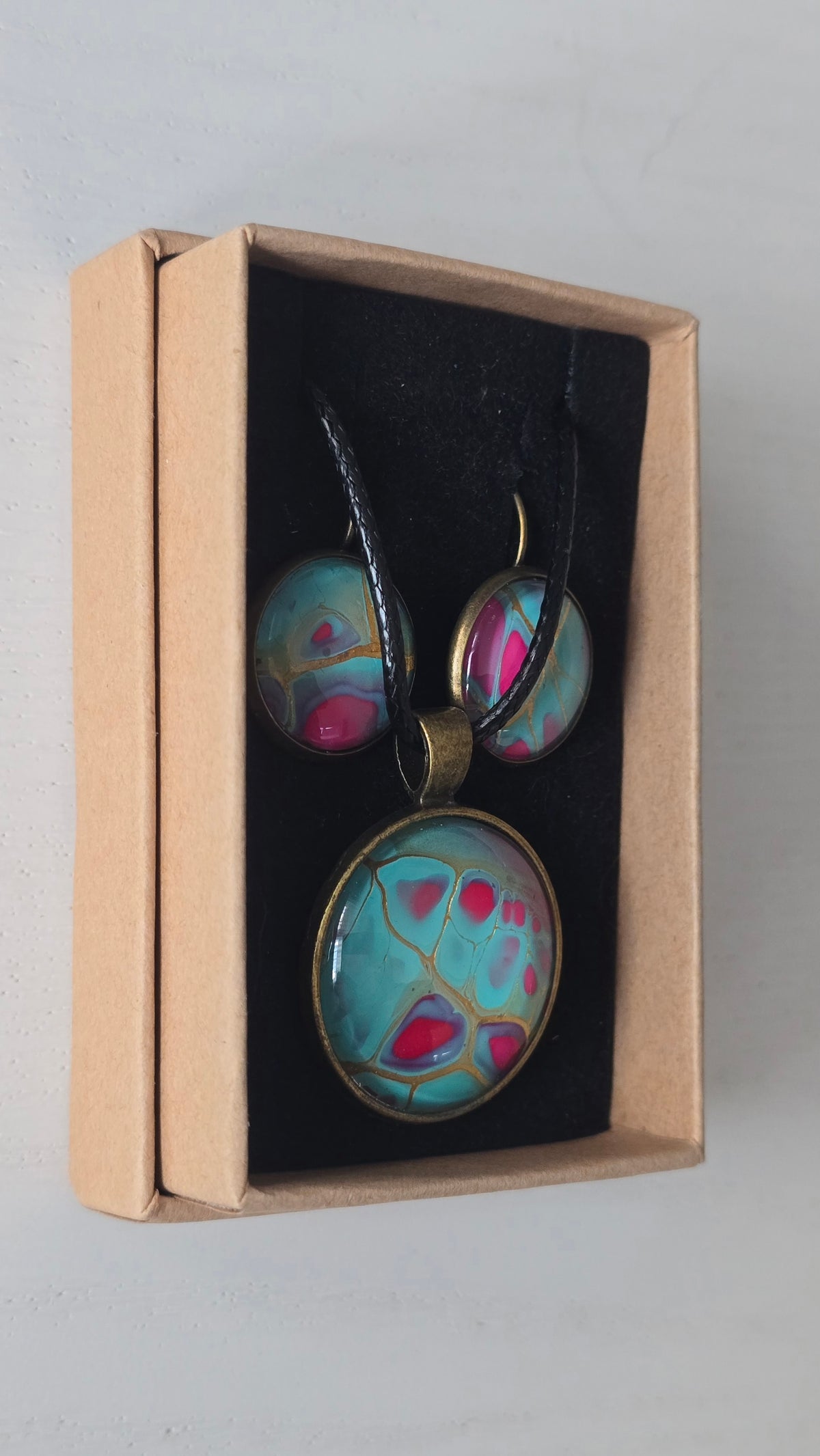 Rundes Cabochon-Schmuckset mit Halskettenanhänger und passenden Ohrringen in Türkis und kräftigem Pink mit feinen goldenen Linien.