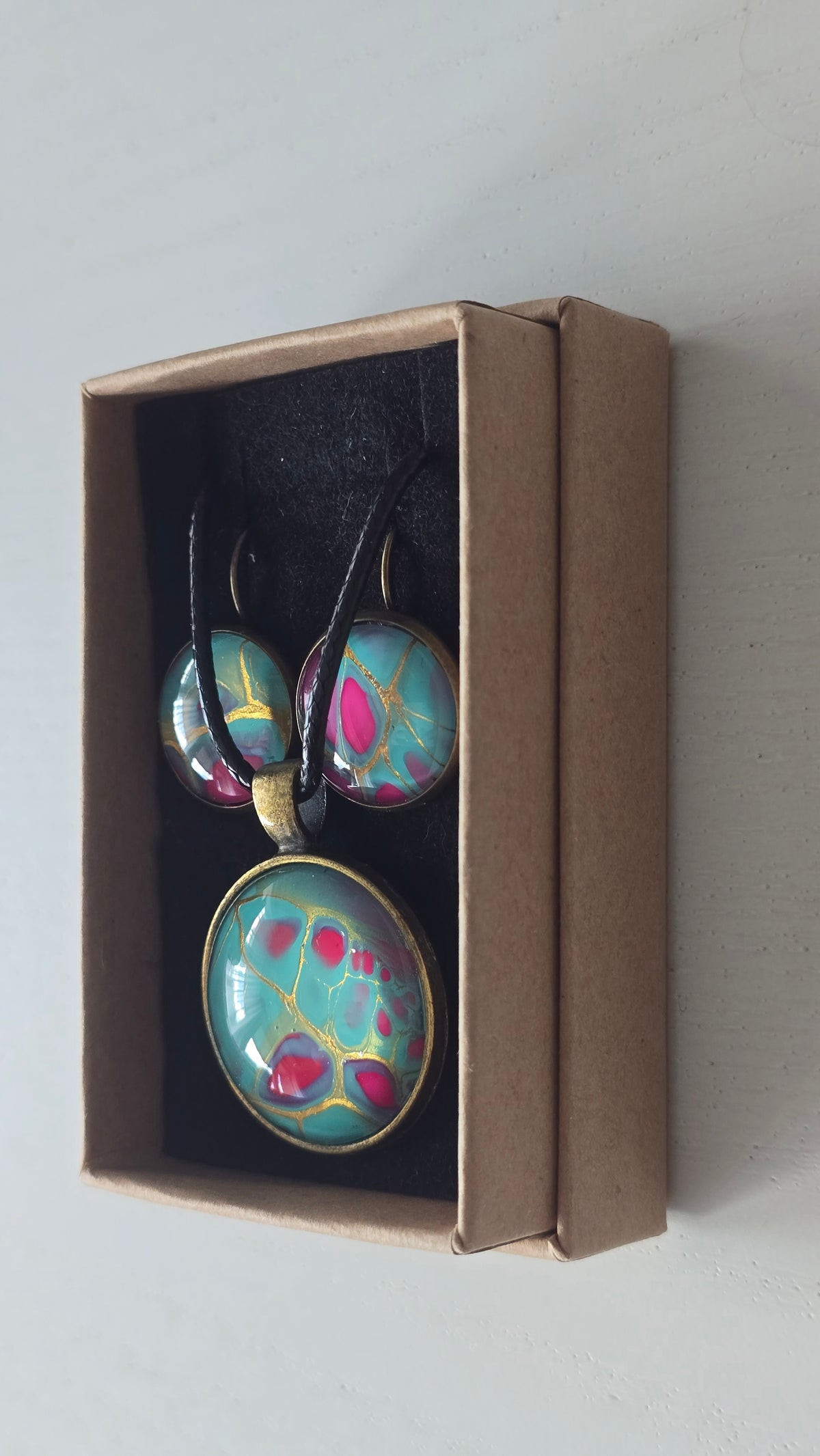 Rundes Cabochon-Schmuckset mit Halskettenanhänger und passenden Ohrringen in Türkis und kräftigem Pink mit feinen goldenen Linien.