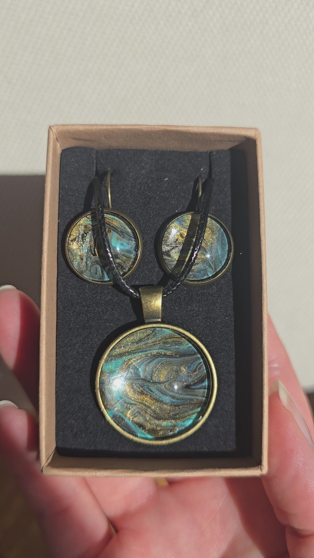 Rundes Cabochon Schmuckset mit Kette und zwei Ohrringen, abstraktes Muster in Schwarz, Türkis, Blaugrün und Gold mit fliessenden Strukturen.