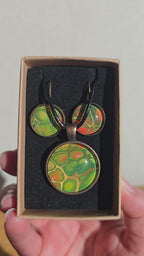 Rundes Cabochon-Schmuckset mit Kette und passenden Ohrringen in verschiedenen Grüntönen, mit orangefarbenen Akzenten und feinen kupferfarbenen Linien.