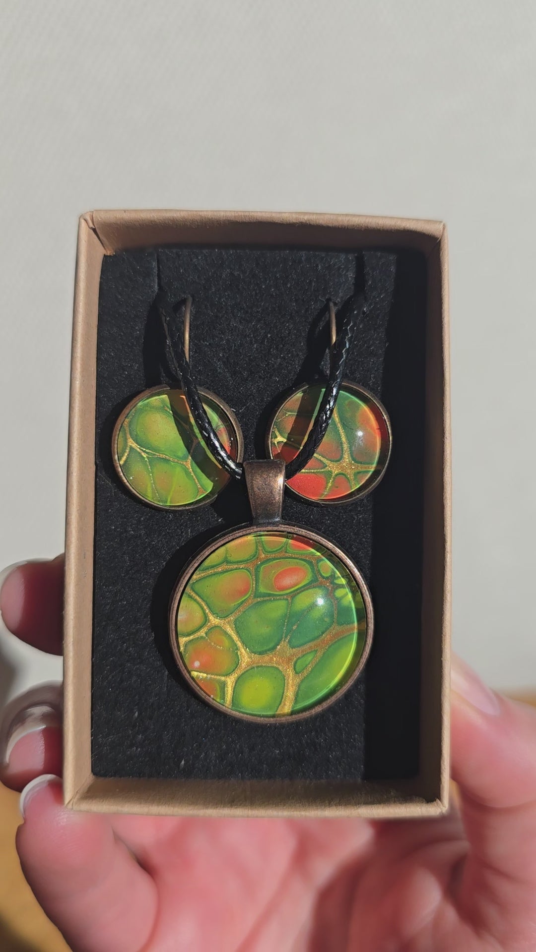 Rundes Cabochon-Schmuckset mit Kette und passenden Ohrringen in verschiedenen Grüntönen, mit orangefarbenen Akzenten und feinen kupferfarbenen Linien.