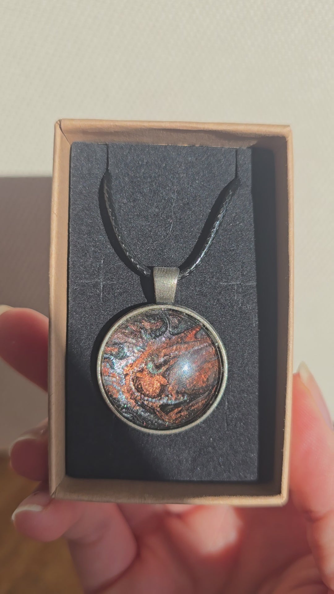 Runde Cabochon Kette Solas Burnt Earth in Kupfer, Bronze und Schwarz mit dunkler Metallfassung und schwarzem Band.