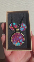 Handgefertigtes Schmuckset Solas Golden Spikes mit runder Halskette und passenden Ohrringen in Violett-, Türkis- und Goldtönen mit markanten goldenen Linien.