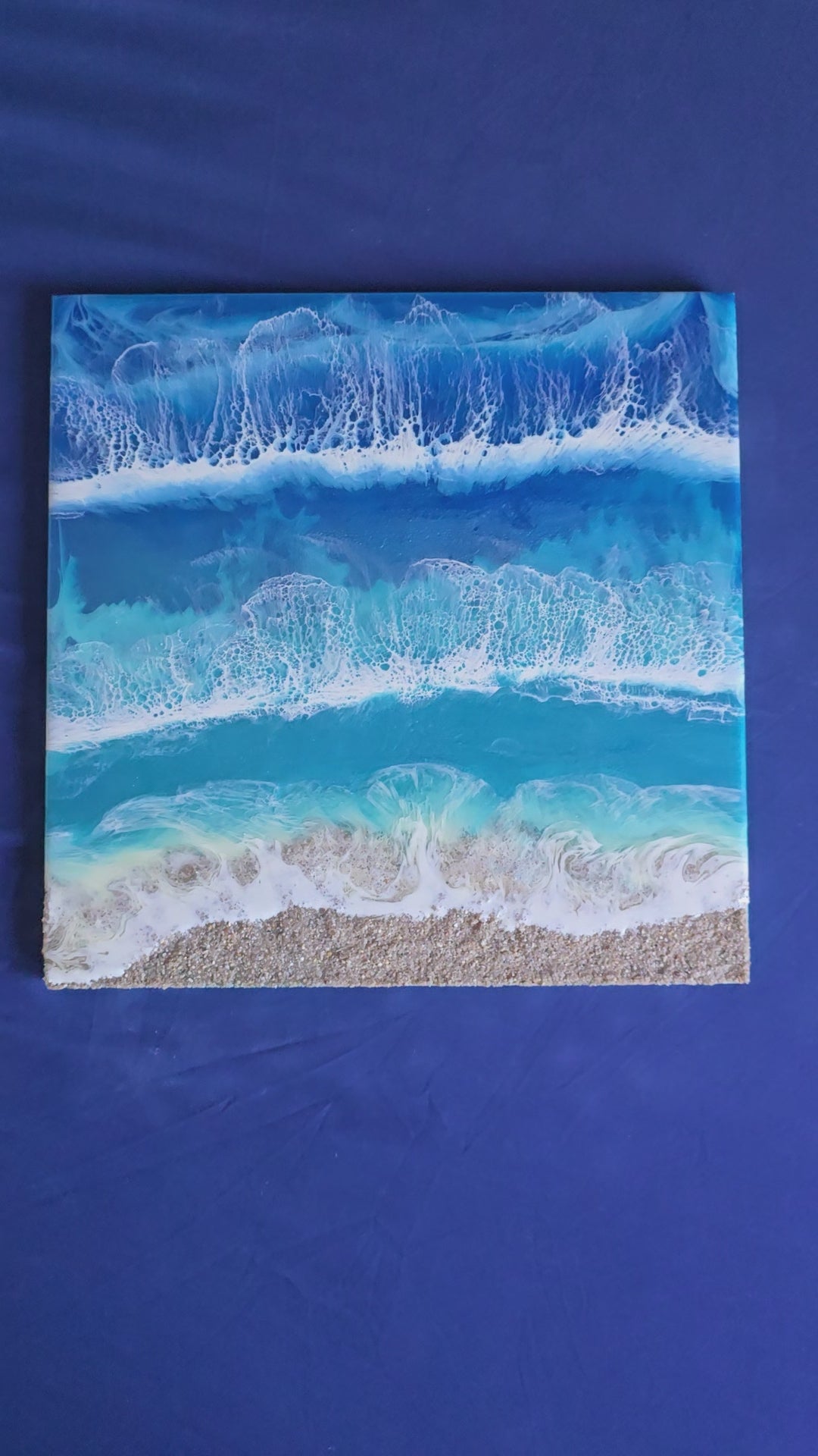Handgefertigtes Resin-Meeresbild Solas Wild Tide (40 × 40 cm) auf einem strukturierten Gesso-Rahmen mit kraftvollen türkisblauen Wellen, natürlichem Sandstrand und schimmernden Perlmutt-Effekten.