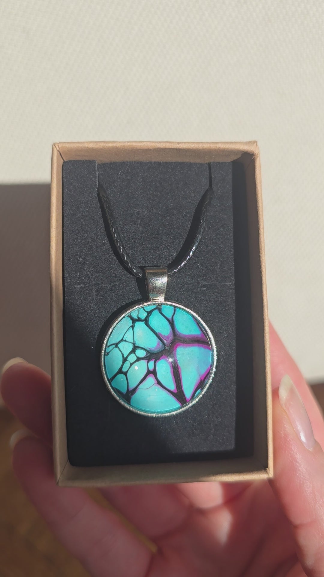Runde Cabochon-Kette in leuchtendem Türkis mit verzweigten Strukturen in Violett, Pink und Schwarz.