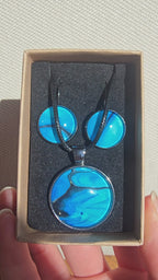 Handgefertigtes Schmuckset Solas Laguna mit rundem Anhänger und passenden Ohrringen in Blau- und Türkistönen mit fliessendem Marmormuster unter Glas.