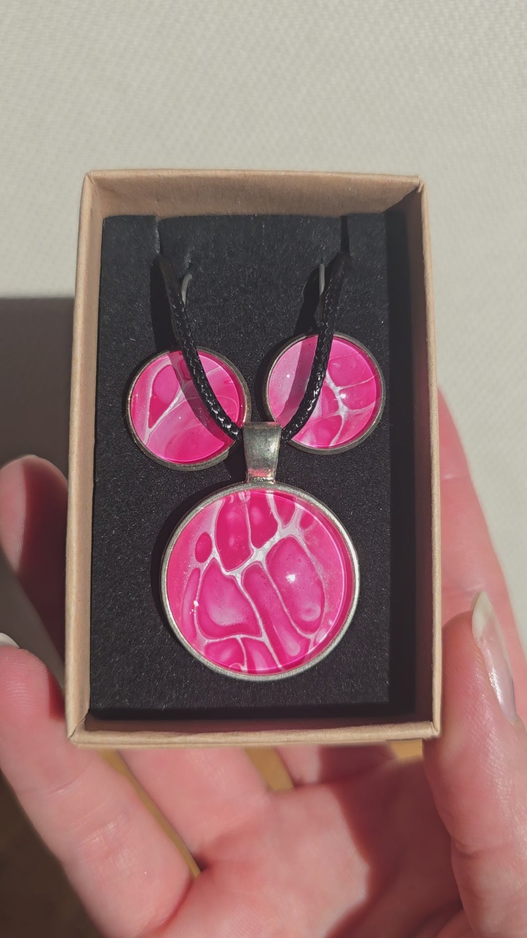 Rundes Cabochon-Schmuckset mit Anhänger und Ohrringen an schwarzem Band, mit organischem Muster in Fuchsia, Himbeerrosa und Pink sowie feinen hellen Linien.