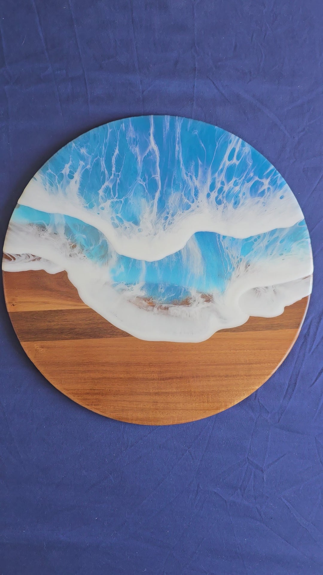 Rundes Resin Wandbild Solas Seafoam auf Holz mit blau-türkisem Meer, weissen Wellen, irisierenden Farbakzenten und sichtbarer Holzstruktur.