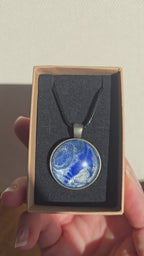 Runde Cabochon Kette Solas Blue Glacier in Kobaltblau, Silber und Weiss mit dunkler Metallfassung und schwarzem Band.