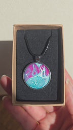 Runder Cabochon-Anhänger an schwarzem Band mit verzweigtem, organischem Muster in Türkis, Aqua, Fuchsia, Pink und hellen Linien.