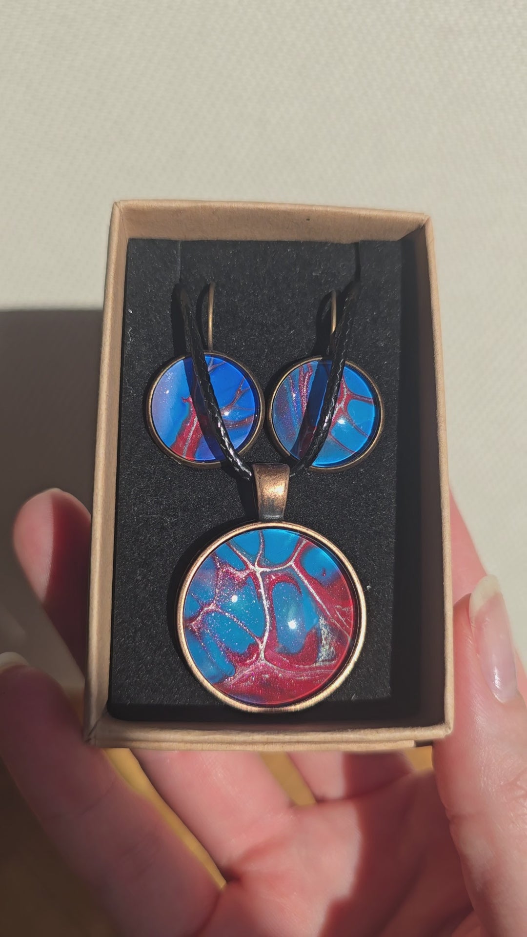 Rundes Cabochon-Schmuckset mit Anhänger und Ohrringen an schwarzem Band, mit verzweigtem Muster in leuchtendem Cyan, Blau, Dunkelrot und Burgunder.