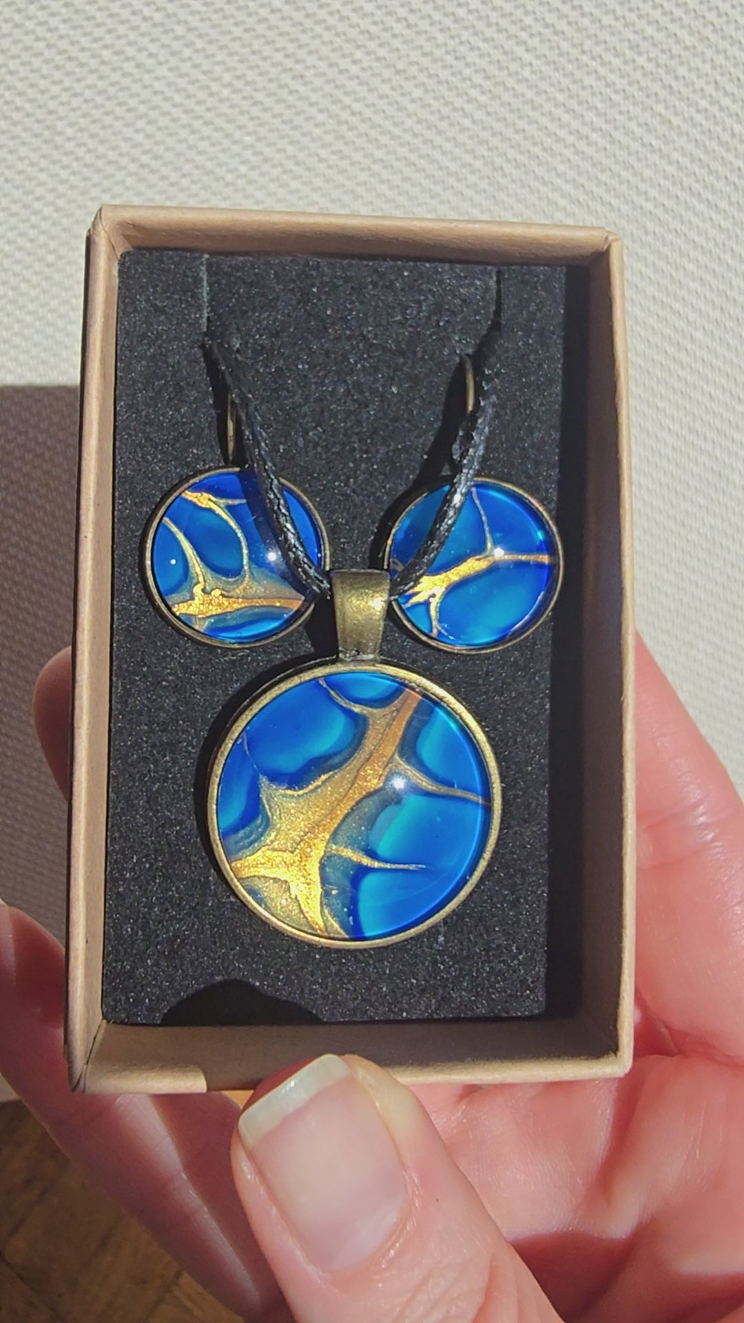Handgefertigtes Schmuckset Solas Deep Current mit runder Halskette und passenden Ohrringen in tiefen Blau- und Goldtönen mit organischer Marmorierung.