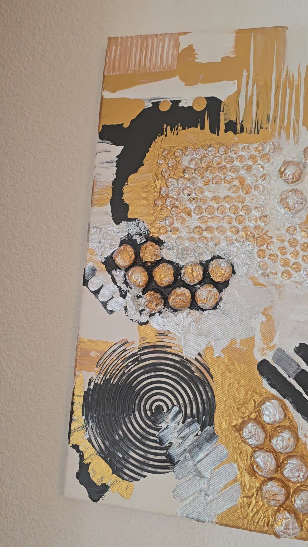 Abstraktes Leinwandbild Aurea 50 × 50 cm mit Gold, Schwarz, Weiss und Perlmutt, geometrischen Formen, Kreisen und plastischen Strukturen.