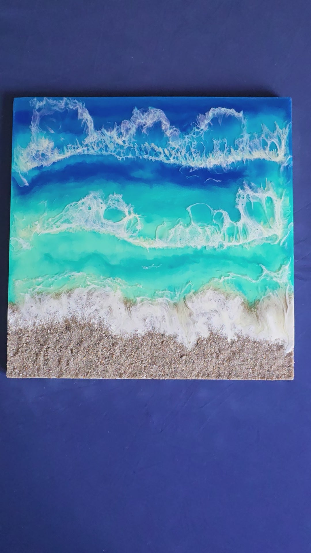 Handgefertigtes Resin-Meeresbild «Solas Turquoise Bay» mit türkisfarbenem Wasser, schäumenden Wellen und natürlichem Kieselstrand auf einem 40 × 40 cm grossen Gesso-Rahmen.