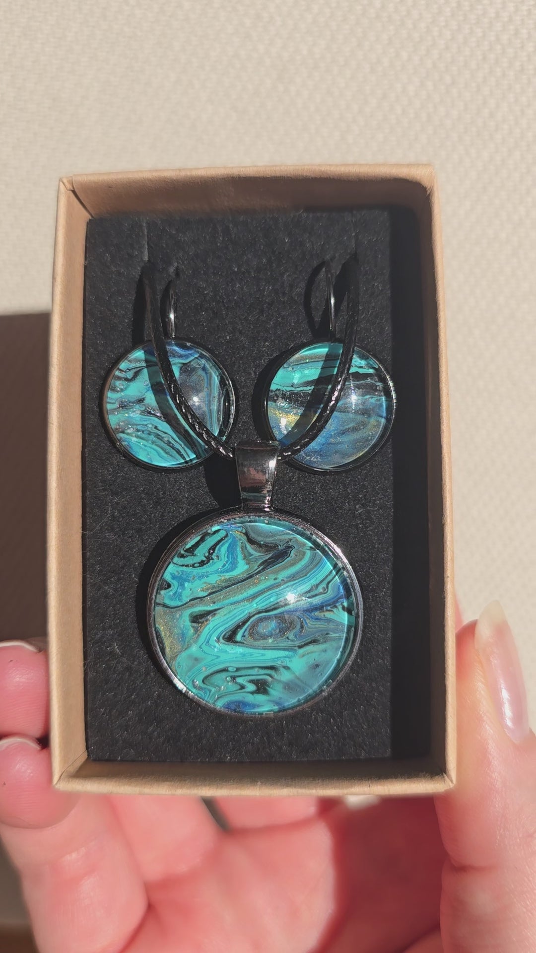 Rundes Cabochon-Schmuckset mit Halskettenanhänger und passenden Ohrringen in Türkis, Blau, Schwarz und Grau mit fliessender marmorierter Maserung.