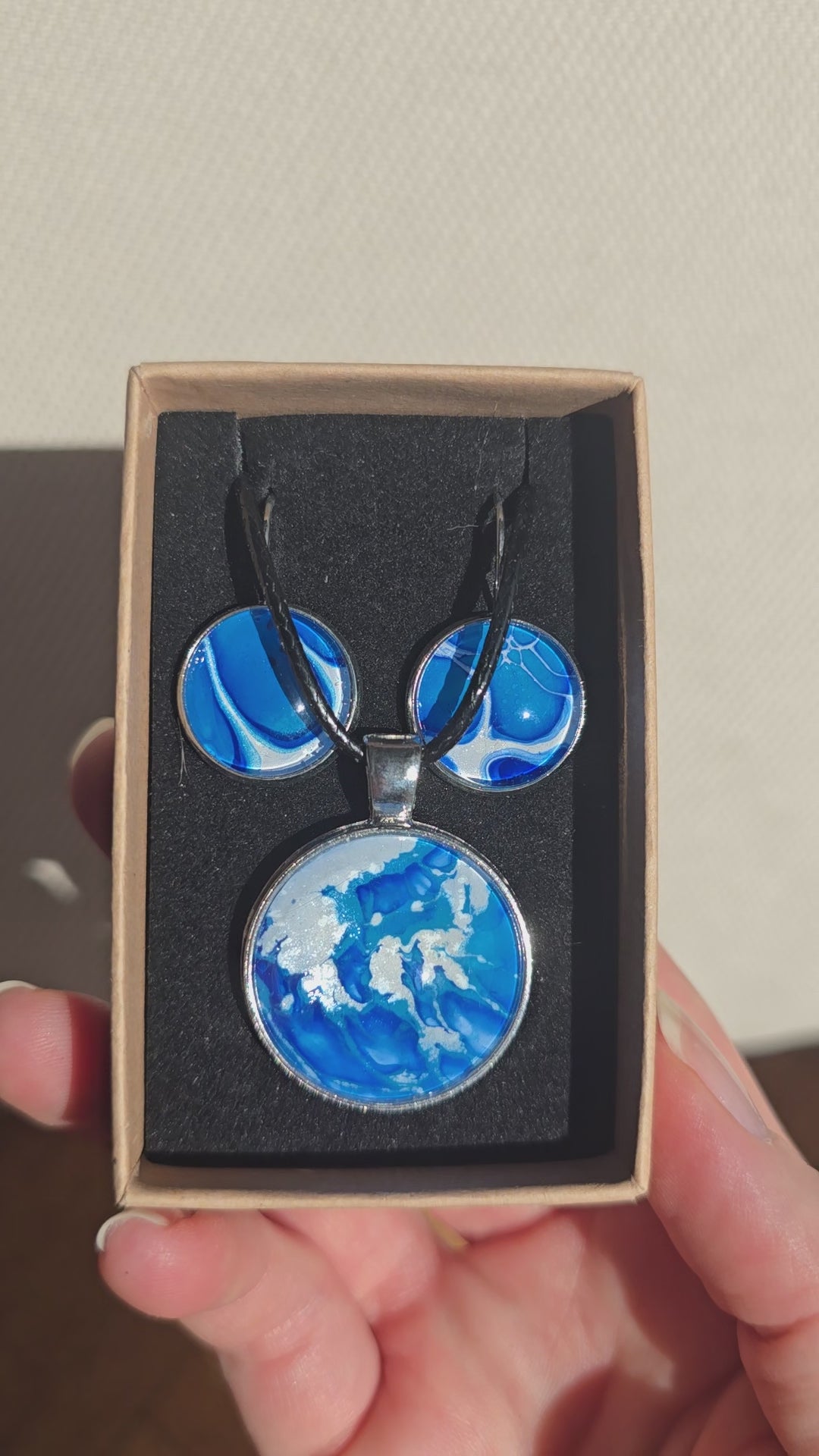 Cabochon Schmuckset Solas Crystal Wave mit runder Kette und passenden Ohrringen in leuchtendem Blau, Türkis und Weiss mit silberfarbenen Fassungen.