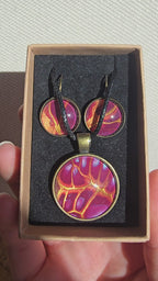 Handgefertigtes Schmuckset Solas Flare mit runder Halskette und passenden Ohrringen in Magenta-, Burgunder-, Orange- und Goldtönen mit leuchtender Marmorierung.
