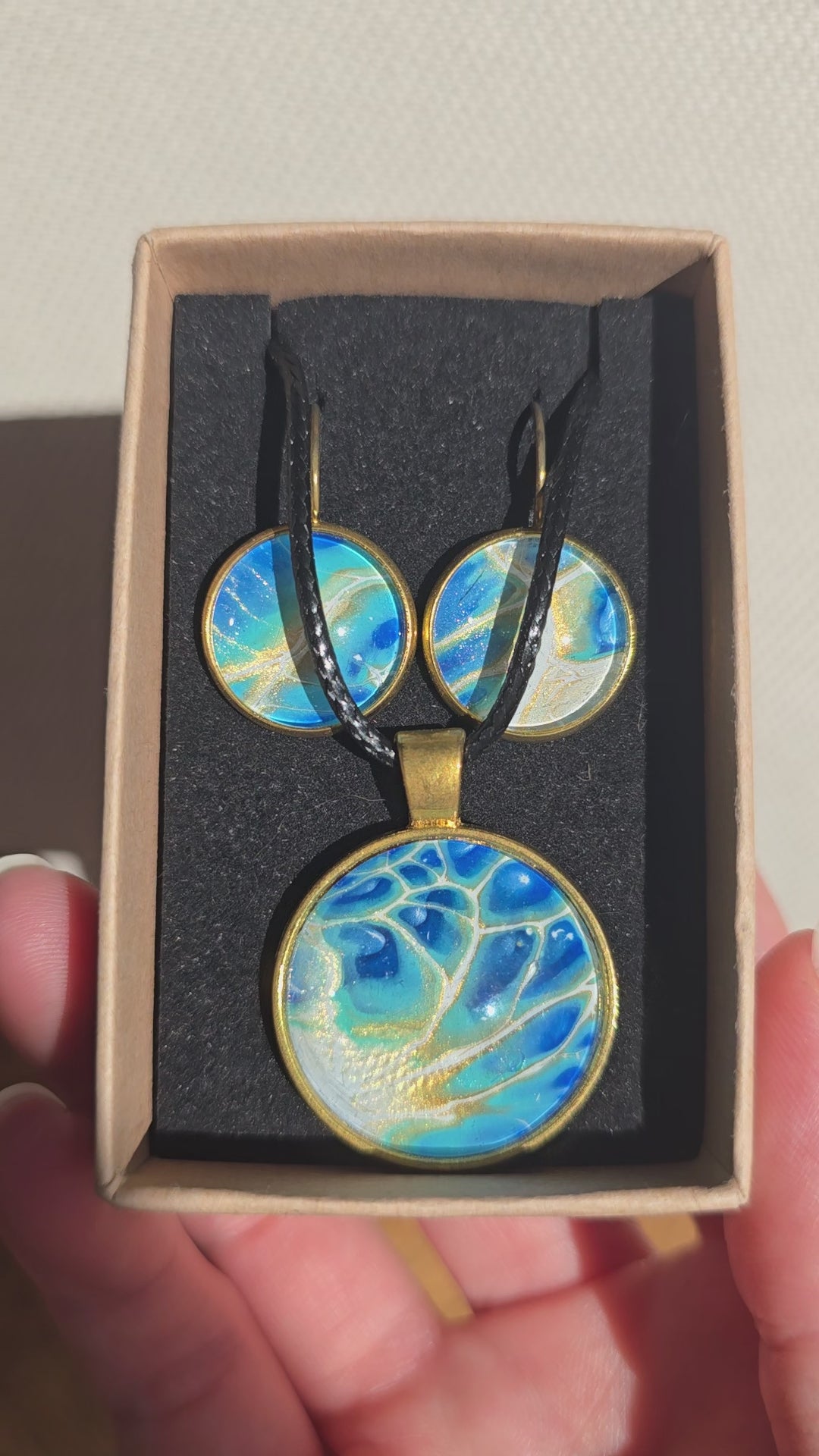 Rundes Cabochon-Schmuckset mit grossem Halskettenanhänger und zwei passenden Ohrringen in Türkis, Blau und Creme mit feinen goldenen Akzenten.