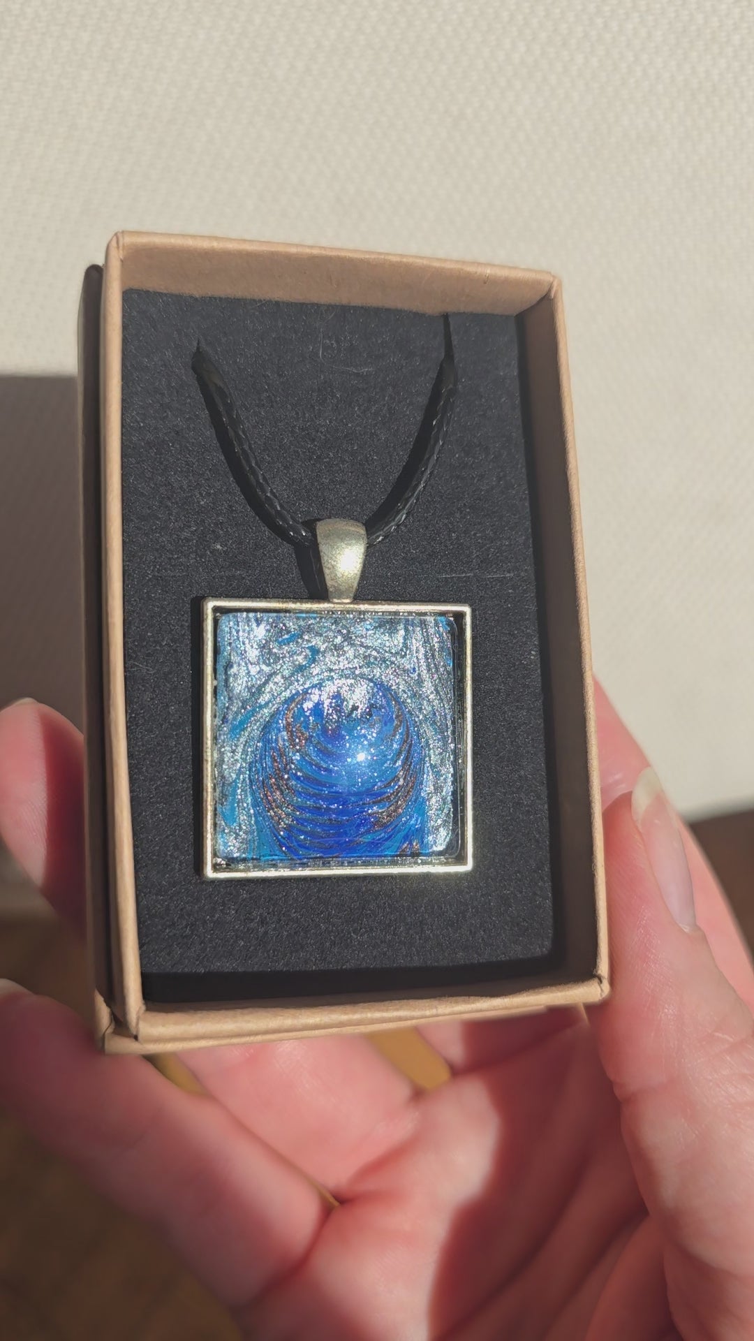 Quadratische Cabochon-Kette mit spiralförmigem, abstraktem Muster in intensivem Blau, Türkis und schimmerndem Silber.