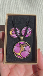 Handgefertigtes Schmuckset Solas Aurora mit rundem Anhänger und passenden Ohrringen in Rosa-, Magenta- und Goldtönen mit fliessendem Marmoreffekt unter Glas.