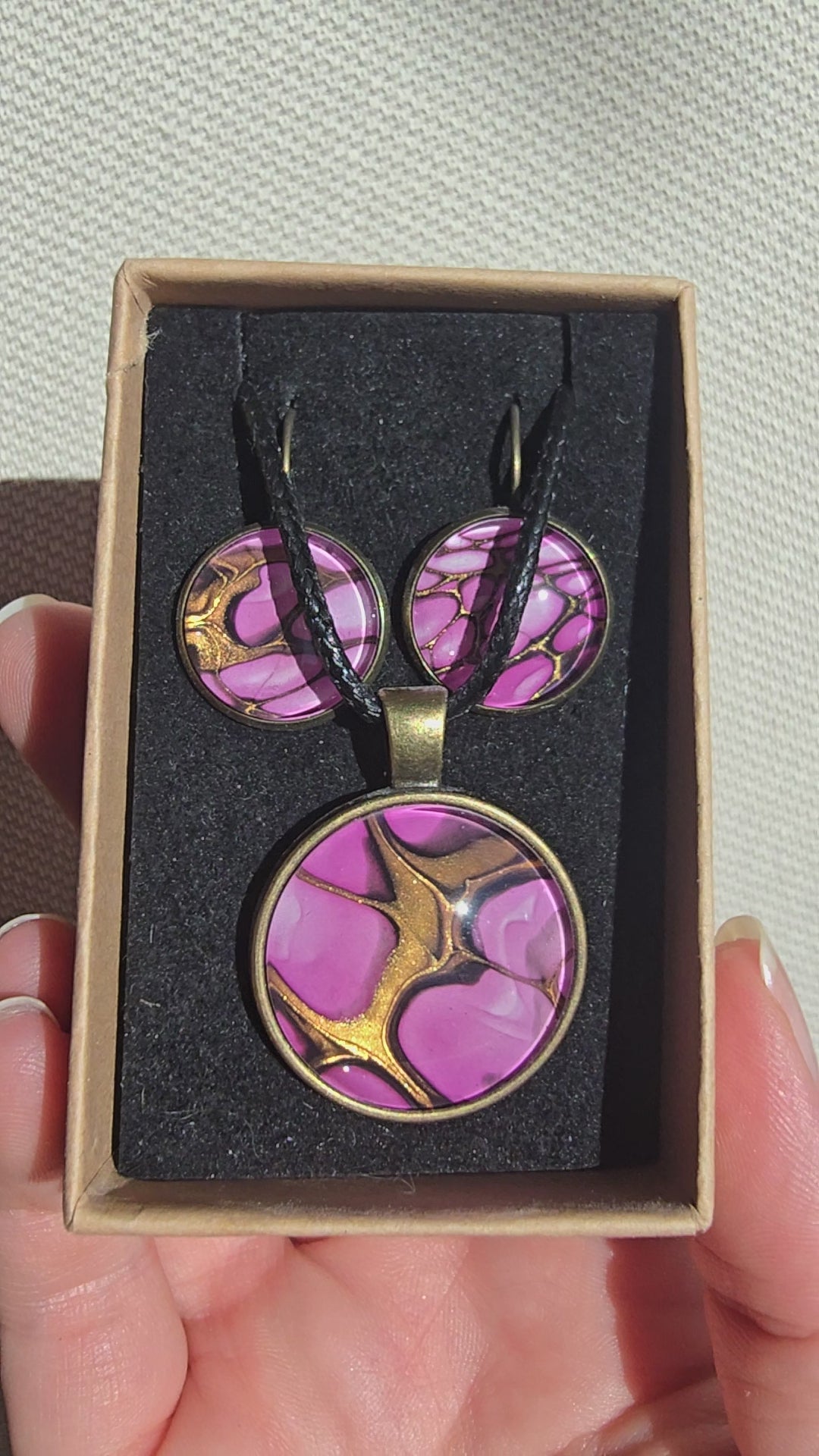 Handgefertigtes Schmuckset Solas Aurora mit rundem Anhänger und passenden Ohrringen in Rosa-, Magenta- und Goldtönen mit fliessendem Marmoreffekt unter Glas.